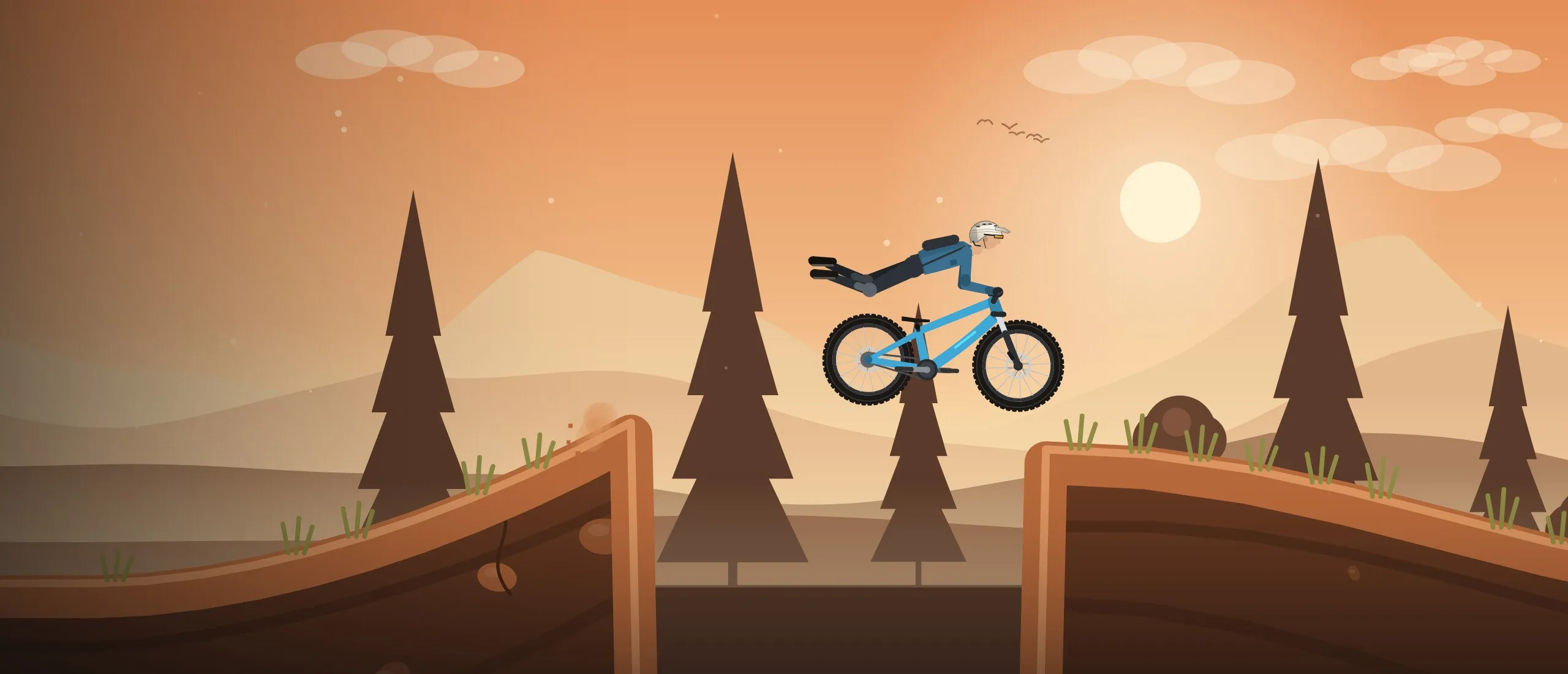 A mountain biker on a blue bike flies over a gap between two dirt ramps doing a superman trick, against an orange sunset.